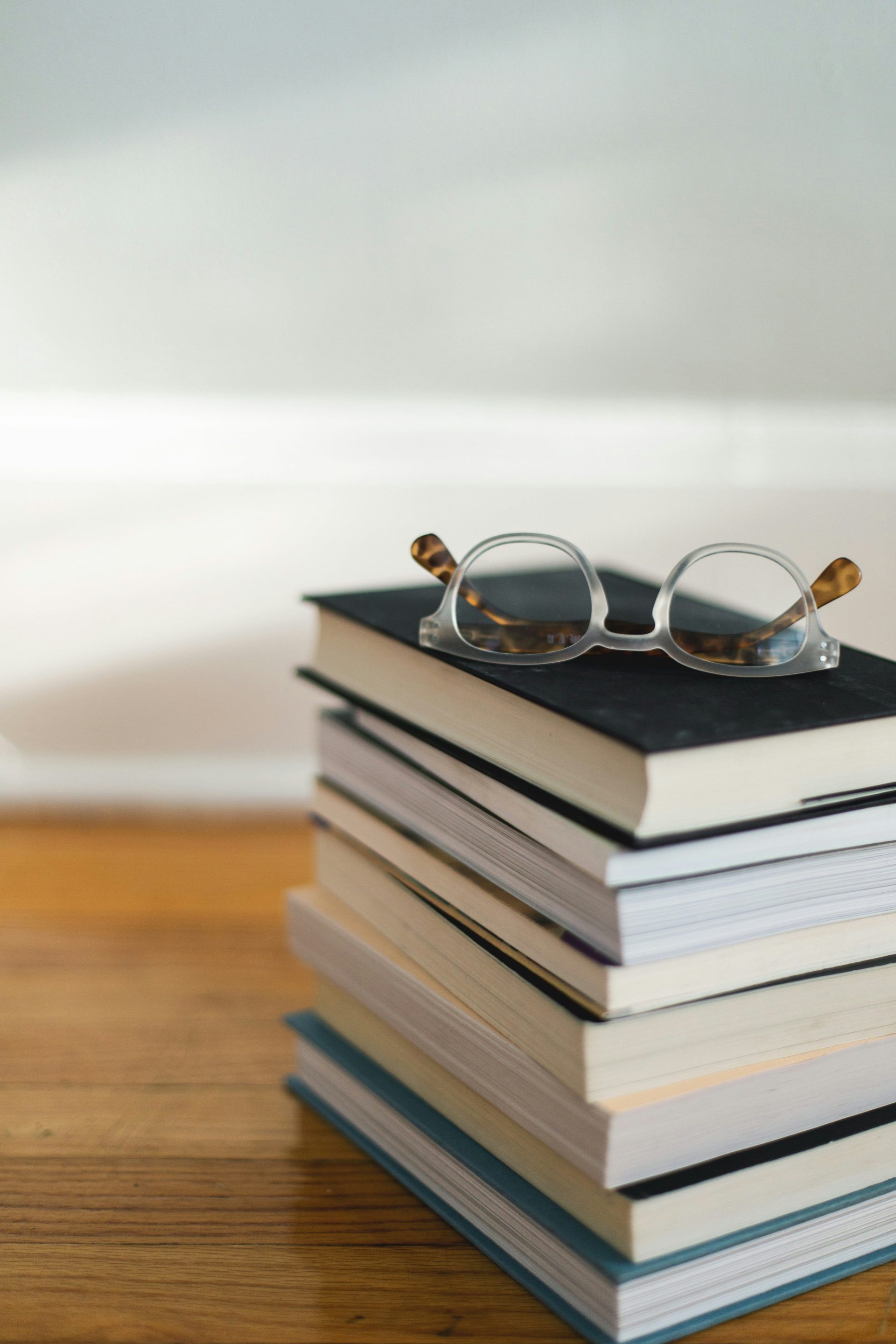 clear framed eyeglasses on top of pile of books